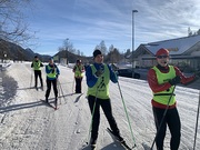 Das Foto zeigt eine Gruppe von Personen, die auf einer gut präparierten, schneebedeckten Strecke im Langlauf aktiv sind. Die Teilnehmer tragen auffällig gefärbte Westen, wobei einige mit dem Aufdruck 'GUIDE' gekennzeichnet sind, was darauf hindeutet,