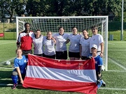 Das Österreichische Team vor einem Tor. Stehend Trainer Asmin Traore, Spielerinnen Rebekka Gottwald, Eva Maria Javornik, Daniela Angerer, Angelika Angerer, Kapitänin Bettina Sulyok und Betreuerin Beate Angerer. Knieend davor: Eva Kirchner und Tanja H