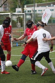 Vier Spieler, zwei in Rot, zwei in Weiß gekleidet, kämpfen um den Ball