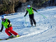ein blinder Skifahrer carvt hinter seinem Guide die Piste runter